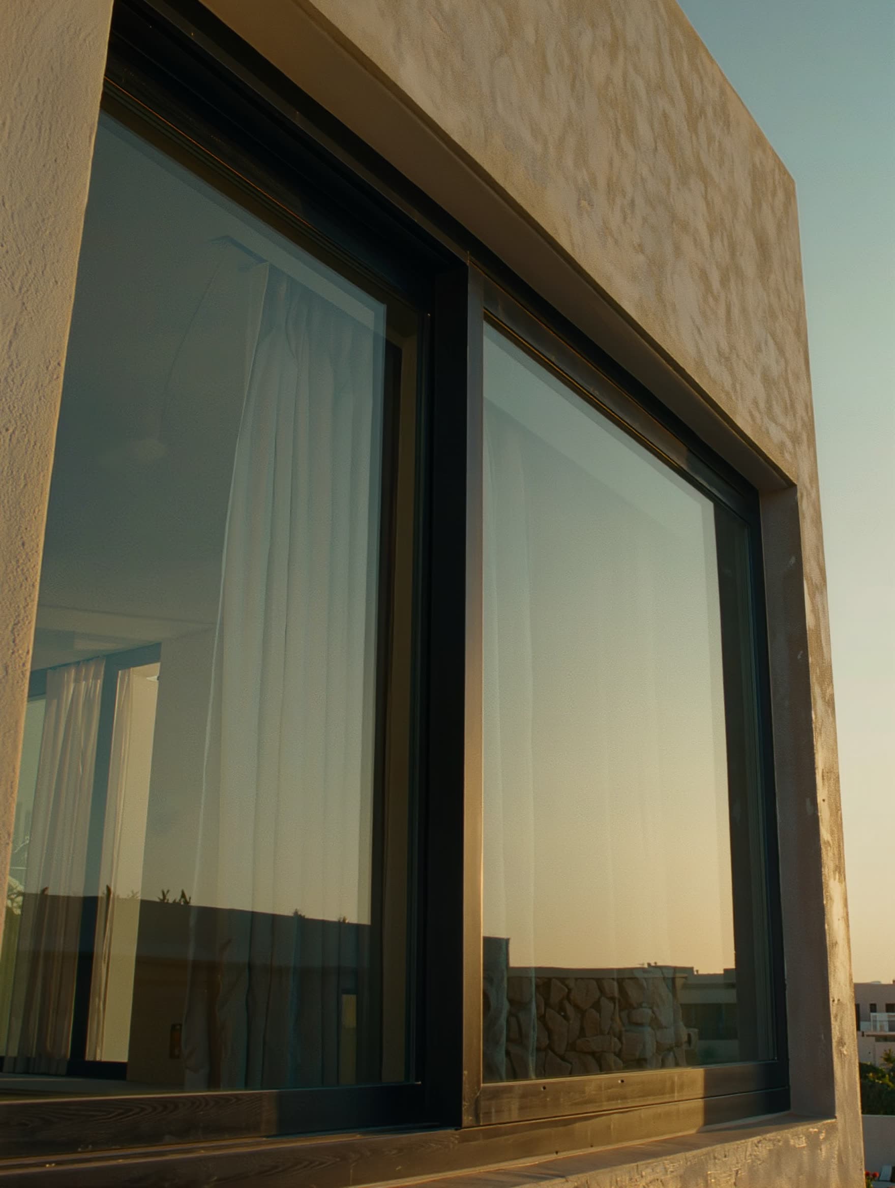 Villa contemporaine à Témara — façade aluminium noir mat, baies vitrées toute hauteur, lumière rasante de fin de journée.